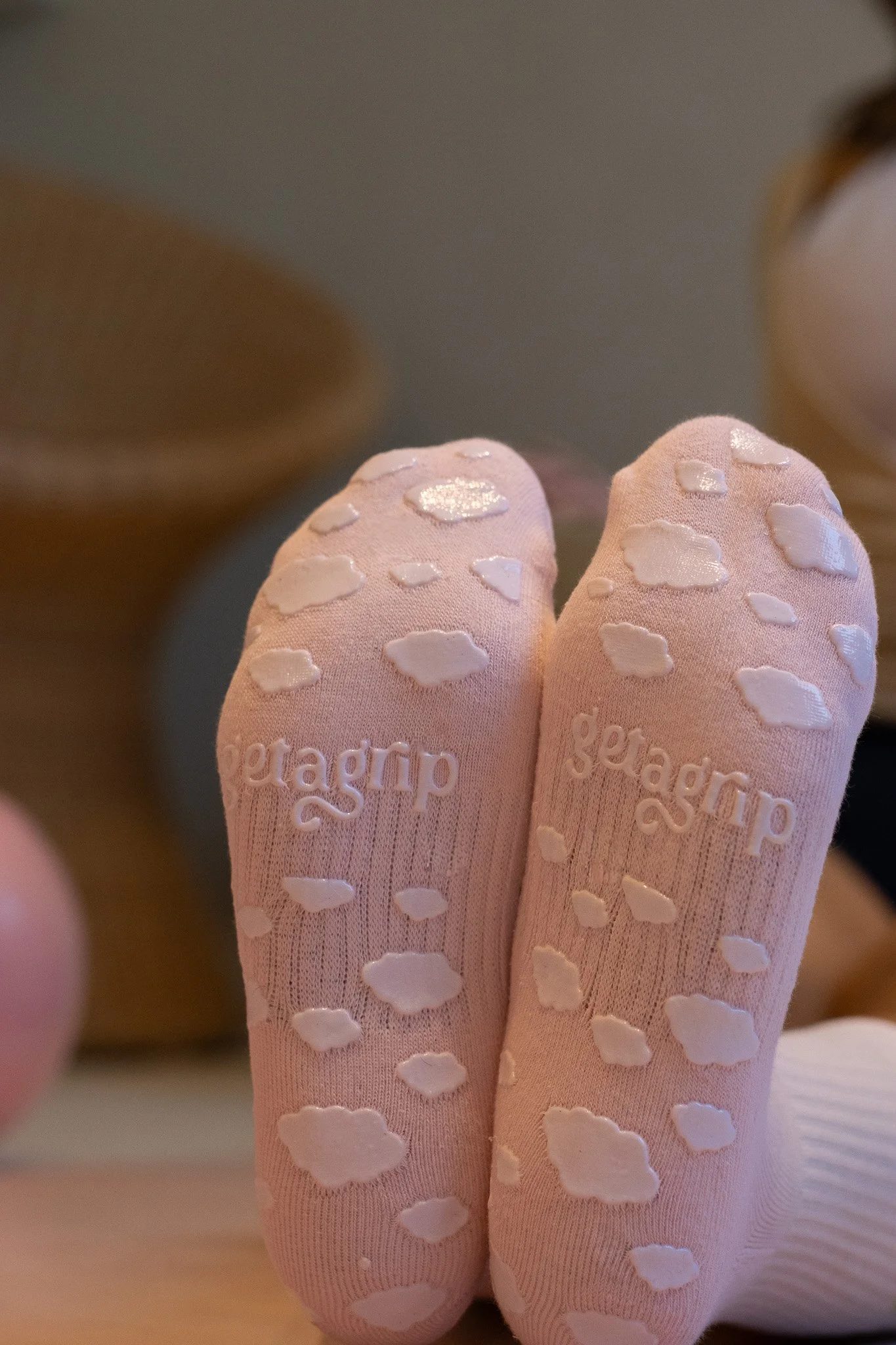 Close-up of pink socks with white heart-shaped patterns, and the word 'geargear' embroidered on them, worn by a person. Shona Manderson, Get A Grip.
