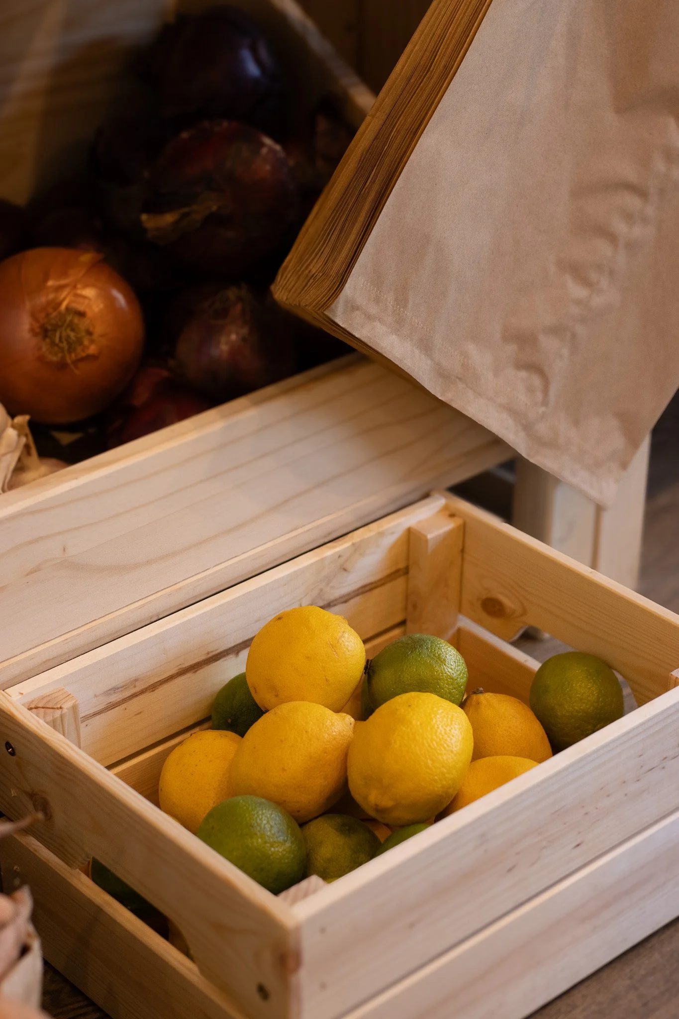Lemon and lime fruits in a wooden crate. The Cotswold Farm. 